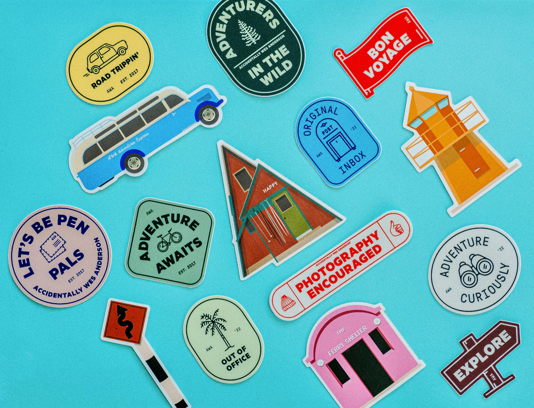 A collection of various die-cut vinyl stickers with different designs, including transportation-themed and adventure-related imagery, displayed on a foil-embossed background.